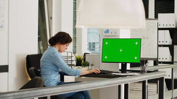 Empty desk with greenscreen layout on computer in coworking space with people solving business operations. Workstation showing computer with isolated copyspace mockup display. photo