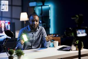 Influencer reviewing mini RGB lights, satisfied with high quality color rendering coming from it. Media star filming content for online channel, excited about excellent video production tool photo