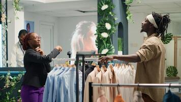 Al por menor trabajador en ropa Tienda utilizando aumentado realidad tecnología a espectáculo cliente prenda opciones para él a elegir. empleado utilizando Arkansas hologramas a ayuda cliente visualizar necesario atuendo foto