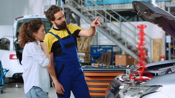 Serviceman in car service uses holographic augmented reality to pinpoint to client vehicle malfunction pitfall. Diligent garage worker uses innovative AR tech to visualize automobile parts for woman photo