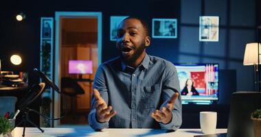 Happy influencer in home studio using professional camera and mic to film live broadcast for online streaming platforms, interacting with fans. BIPOC online star hosts q a session with viewers photo