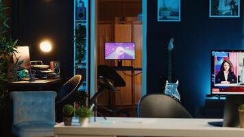 Computer screens showing abstract animation rendering in dimly lit empty home interior. 3D renders on digital displays in neon illuminated cozy apartment living room with TV running in background photo