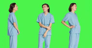 Asian person medical assistant in studio wearing hospital uniform clothing, posing with confidence and having professional healthcare expertise. Young guy with career in medicine. photo