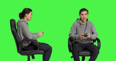 Asian gamer playing video games over greenscreen background, using controller and enjoying gameplay with friends online. Young person having fun with rpg competition on console. photo