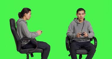 Asian gamer playing video games over greenscreen background, using controller and enjoying gameplay with friends online. Young person having fun with rpg competition on console. photo