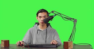 Asian guy does playtime livestream while sitting at workstation and playing online combat video games with his friends. Young man uses microphone to record live broadcast on his desktop pc. photo