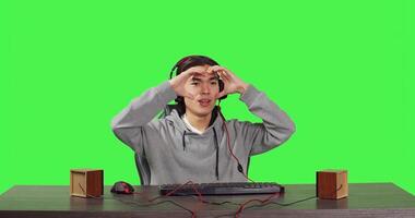 POV of man playing online videogames at computer while he enjoys gameplay with his friends, using headphones at desk. Asian player having fun with adventure game at workstation, greenscreen. photo