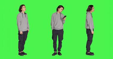 Dissatisfied man in studio awaiting a thing, wandering about and monitoring time on watch against full body greenscreen backdrop. Asian person annoyed and frustrated, looks at his timepiece. photo