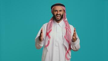 Confident man cheering and presenting his support in front of camera, feeling optimistic and happy about something. Middle eastern guy being brave and strengthening forces with cheers. photo