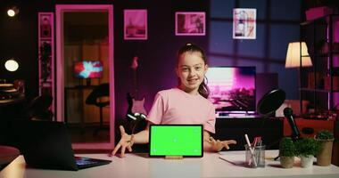 Smiling daughter filming online content with her parent using green screen tablet from sponsoring brand. Happy kid and her mother do internet videos for fans using chroma key device photo
