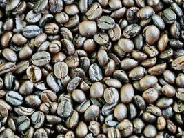 Texture of coffee beans, beans slices of green leaves. beautiful light, vigor of coffee beans, among coffee bushes, Roasted coffee beans on old wooden table photo