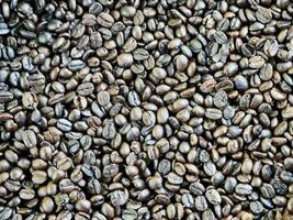 Texture of coffee beans, beans slices of green leaves. beautiful light, vigor of coffee beans, among coffee bushes, Roasted coffee beans on old wooden table photo