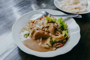 Javanese vegetable salad with peanut sauce gado-gado served with egg and shrimp cracker. Black wooden background. photo