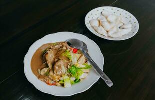 Javanese vegetable salad with peanut sauce or gado-gado served with egg and shrimp cracker. Black wooden background. photo