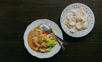 Top view of Javanese vegetable salad with peanut sauce gado-gado served with egg and shrimp cracker. Black wooden background. photo