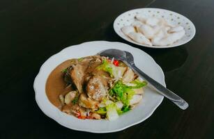 Javanese vegetable salad with peanut sauce gado-gado served with egg and shrimp cracker. Black wooden background photo