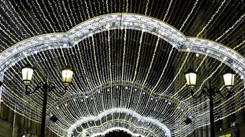 navidades ligero decoración en el ciudad calle a noche. concepto. nuevo año guirnaldas y antiguo linternas en negro cielo antecedentes. foto