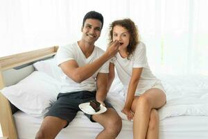 Smiling and happy couple having dessert in bed in the morning photo