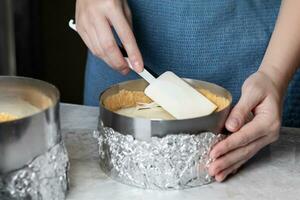 Woman making cheesecake, she lays the cheese layer, close up photo food