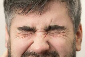 Man winces grimace of pain on the face close up photo