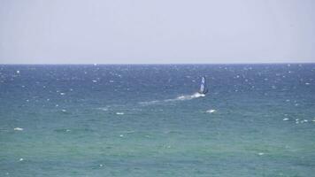 Windsurfer riding the waves in the sea. Shot. Windsurfer in the sea, man on windsurf conquering the waves, enjoying extreme sport, active lifestyle, happy summer vacation photo