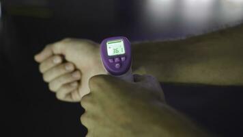 Person measuring temperature with thermometer of another person. Media. Close up of male hand using non contact infrared thermometer for Coronavirus prevention. photo