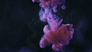 A beautiful mixture of acrylic inks in dark blue glittering water. Stock footage. Close up of pink ink stream forming amazing cloud while mixing with water. photo