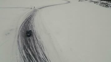 Winter fun filmed from a helicopter. Clip. Winter drift in cars that go to competitions and people watching around. photo