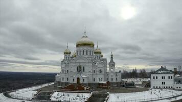 Aerial view of a white church with golden domes on a winter cold day. Clip. Concept of religion and architecture. photo