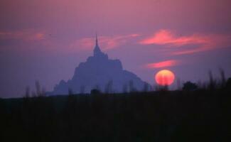 the sun sets behind a mountain in the background photo