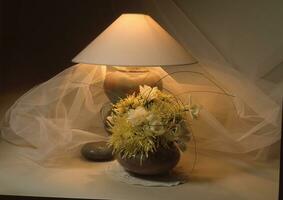 un florero con flores y un lámpara en un mesa foto