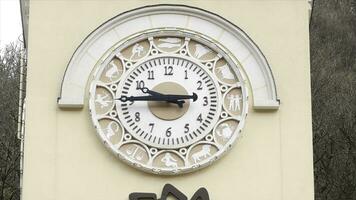 Close up of old tower of beige color with white clock dial surrounded by signs of zodiac. Stock footage. Architectural details of old clock tower. photo