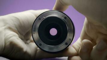 Close-up of man rotating lens. Action. Photographer turns ring of professional lens on isolated background. Lens of lens changes size from rotation of ring by photographer photo