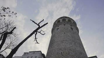 Bottom view of Galata Tower. Action. Ancient stone tower on background of blue sky. Historical stone tower in center of Istanbul. Architectural sights of Istanbul photo