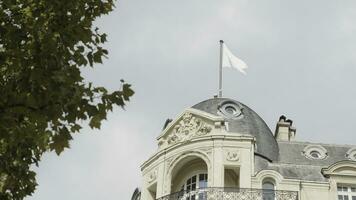 France, Paris - July 29, 2022. Bottom view of old European house with green tree. Action. Exterior of old building with Apple flag in Paris. House on Champs-Elysees with Apple Store photo