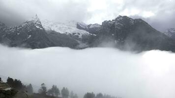 Beautiful mountain landscape with thick clouds. Creative. Rocky snowy mountain peaks with cloudy clouds. Low cumulus clouds in snowy mountains in autumn photo