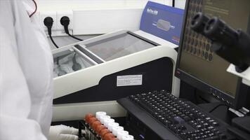 Female medical or scientific researcher using test tubes on laboratory. Clip. Female Scientist Analyzes Liquid in the Beaker and Types Down Observations on Her Computer. She's Working in a Laboratory photo