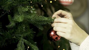 Close-up of woman's hand hanging Christmas toy. Decorating Christmas tree. New year and Christmas holidays concept photo