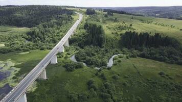 Aerial view of highway with trees and mountain. Clip. Top view of the asphalt road in forest area photo