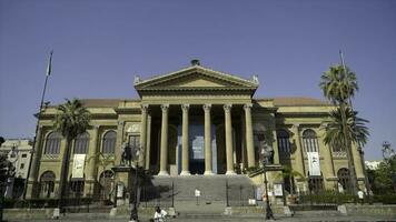 Facade of ancient building with columns and triangular portico. Action. Beautiful historical building with antique architecture and columns on blue sky background photo