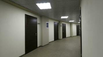 Empty, round corridor with light beige walls and closed, dark brown doors. Closed doors along a lighted corridor in the office building. photo