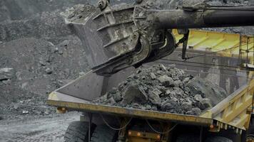 Excavator fills dump truck. Bucket excavator closeup loads stones into body of dump truck on mining or construction of something photo