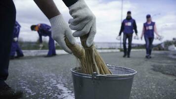 manos inmersión pintar dentro un lleno pintar taza. acortar. de cerca de un trabajador su cepillo dentro el pintar. trabajadores en azul inmersión el cepillo en el pintar foto