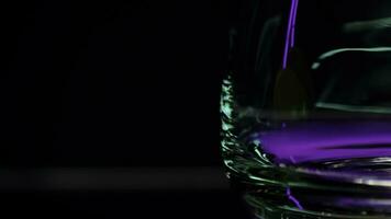 Close up of empty transparent glass with the reflection of lights. Stock clip. Wall with colorful illumination of a night bar. photo