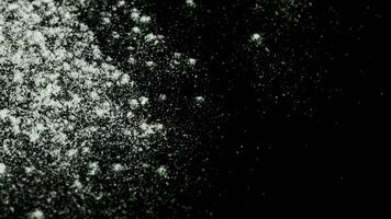 White powder falling down isolated on black background. Stock footage. White dry inks dropping on dark surface. photo