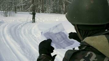 Soldier with weapons in cold forest. Winter warfare and military concept. Clip. Soldiers in winter forest on skis with guns. Military exercises in the forest in slow motion photo