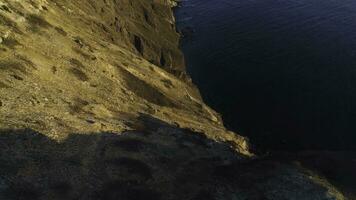 aéreo ver de rock acantilado y el rodeando mar agua en puesta de sol cielo. disparo. escarpado Pendiente de montaña cerca el calma mar , belleza de naturaleza. foto