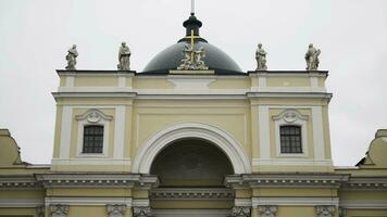 Yellow facade of Church on background cloudy sky. Action. Beautiful details of facade of Catholic Church in yellow with statues. Saint Catherine's Catholic Church in Saint-Petersburg photo