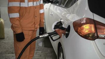 Gas Station Worker Refilling Car at Service Station. Clip. Male gas attendant fills the car photo