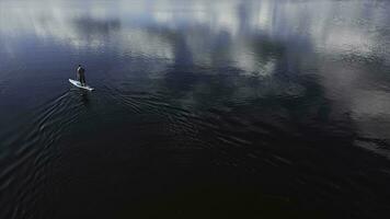 Athlete rowing on the Board paddle, outdoor activities on the water. Footage. Aerial top view of a sports man with a paddle leaving ripples behind him. photo